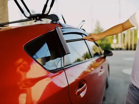 A squeegee drawn down the side window of a red hatchback